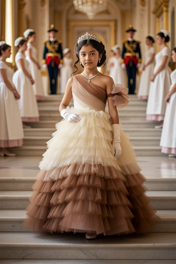 A Young girl in a princess brown flared gown from Nibblekins standing on a staircase with other formally dressed individuals in the background.