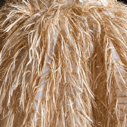 Close-up of a voluminous tiki-style straw hat with natural tan raffia and white woven trim.