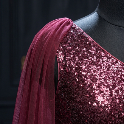 A close-up of a dark mannequin torso wearing a one-shoulder embellished top with a sheer draped fabric. The top is covered in pink and burgundy sequins, and the fabric is a matching deep pink mesh.