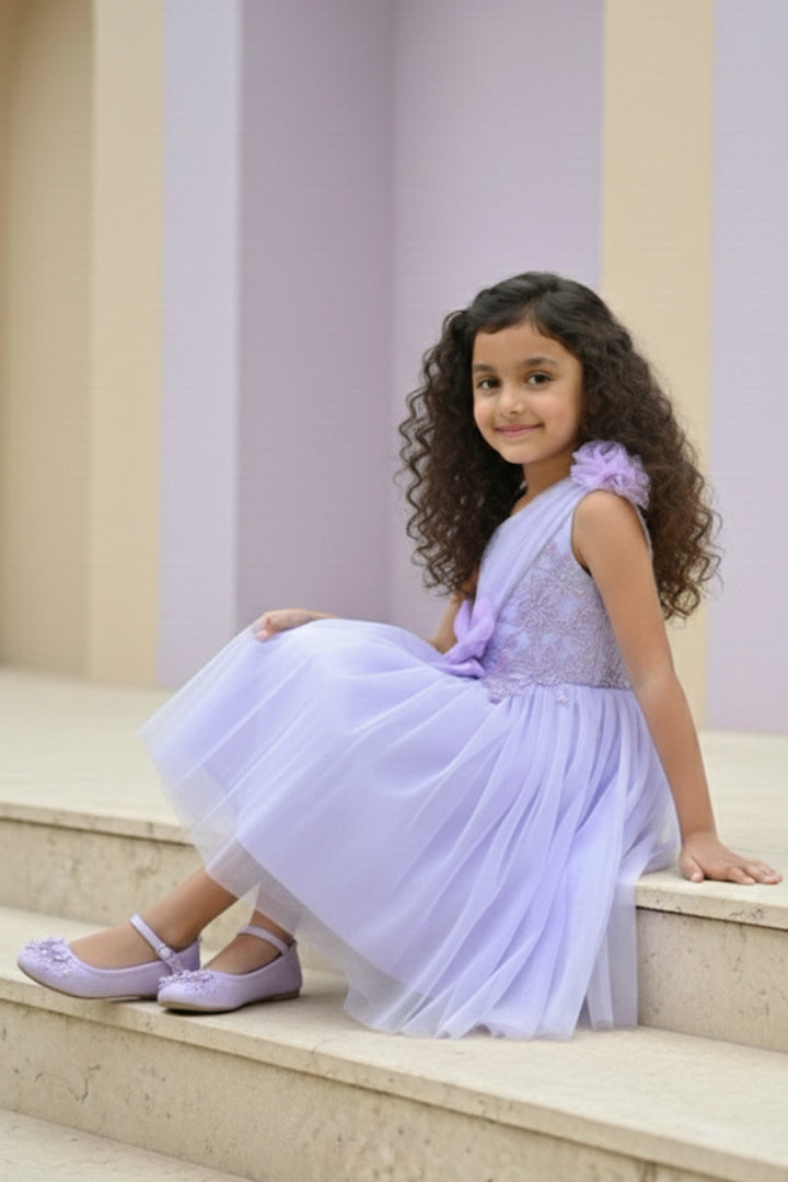 A Young girl in a lavender dress from Nibblekins sitting on the steps with a neutral background