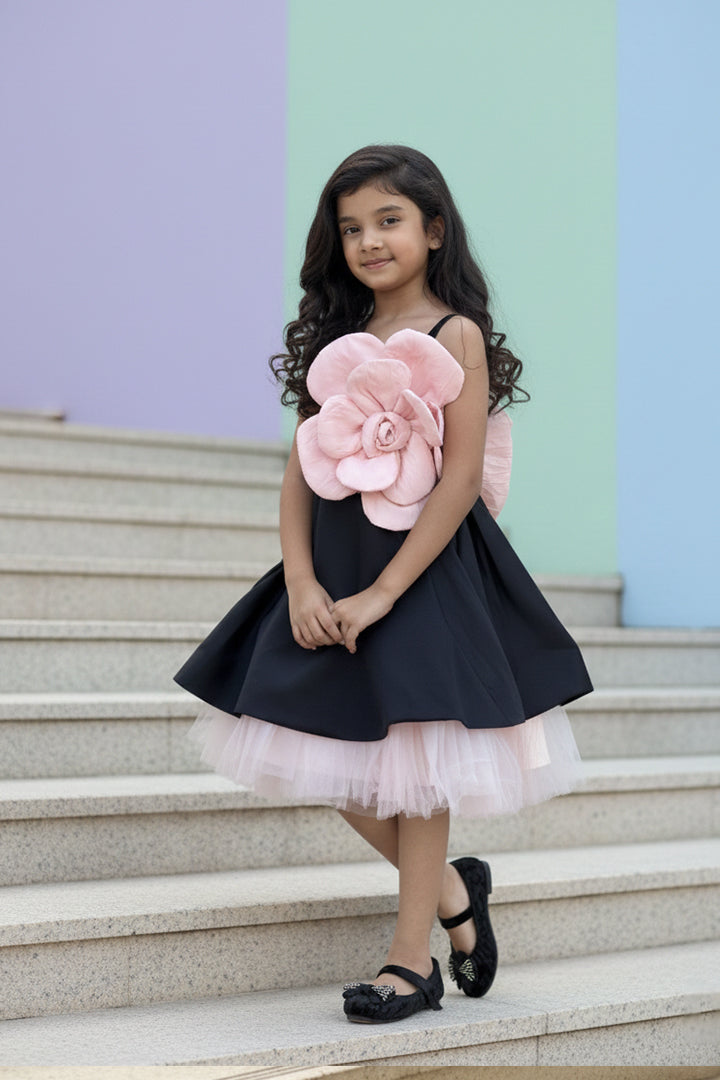 A young girl in a black dress with a large pink flower from Nibblekins standing on the steps.