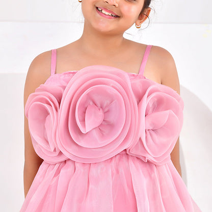 Young girl wearing a pink dress with a large floral design on a white background