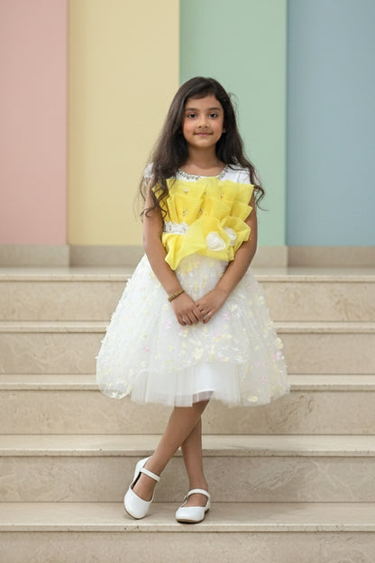 Young girl in a yellow and white dress from Nibblekins standing on steps with pastel-colored walls in the background