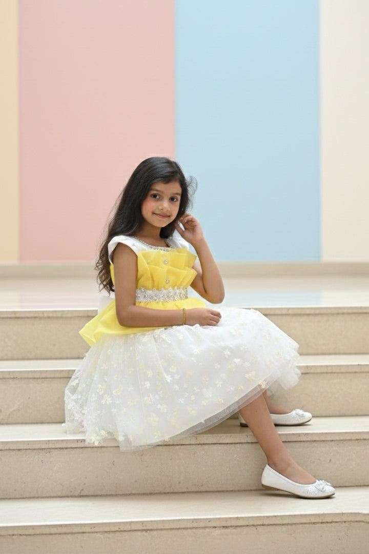 Young girl in a yellow and white dress from Nibblekins sitting on steps with colorful walls in the background