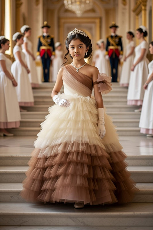 A Young girl in a princess brown flared gown from Nibblekins standing on a staircase with other formally dressed individuals in the background.
