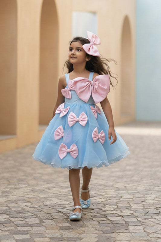 A young girl in a blue dress with pink bows from Nibblekins walking outdoors.