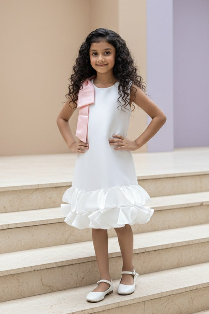 Young girl in a white dress from Nibblekins with a pink Bow standing on the steps.