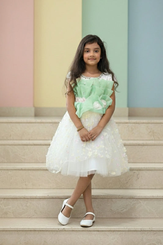 Young girl in a green and white dress standing on steps with a colorful wall background