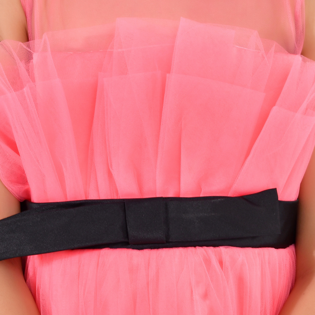 A close-up of a bright pink tulle dress with a wide black satin bow tied around the waist.