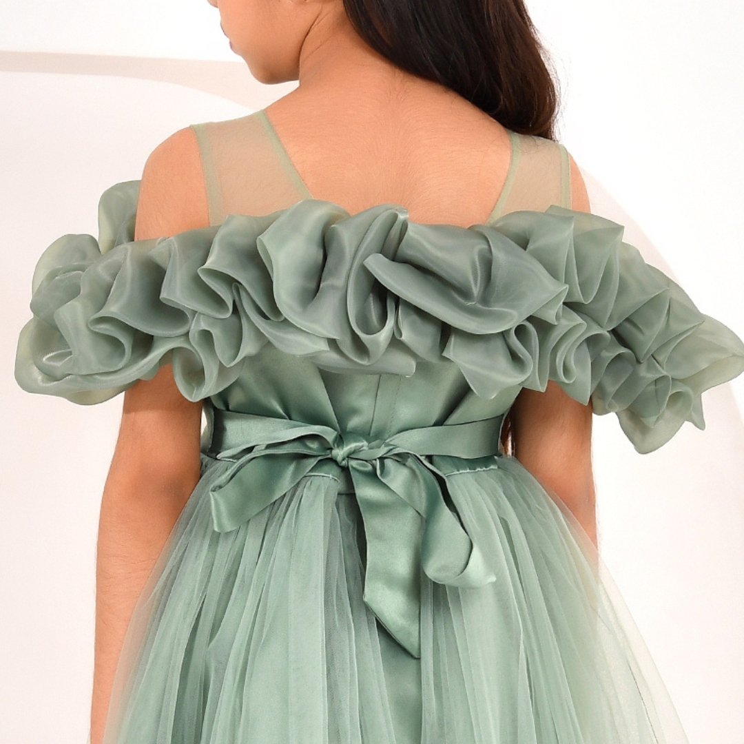 A sage green off-the-shoulder tulle dress with a ruffled organza bodice and a matching satin waist tie, shown on a model from the back.