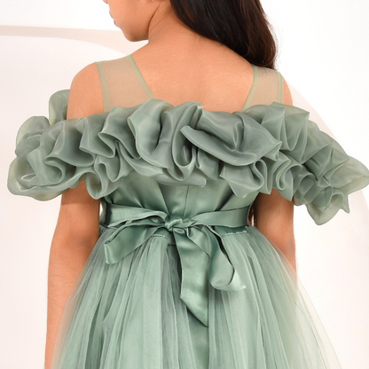 A sage green off-the-shoulder tulle dress with a ruffled organza bodice and a matching satin waist tie, shown on a model from the back.