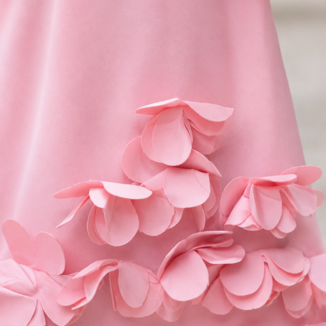A close-up of a light pink scuba fabric with layered 3D paper flower appliqués along the lower edge.