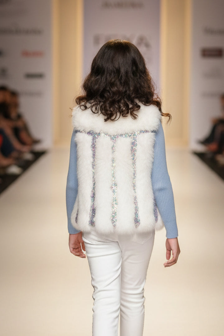 A model wearing a white fur jacket from Nibblekins and a light blue sweater on a runway 