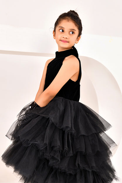 Young girl wearing a black dress with a layered skirt on a white background