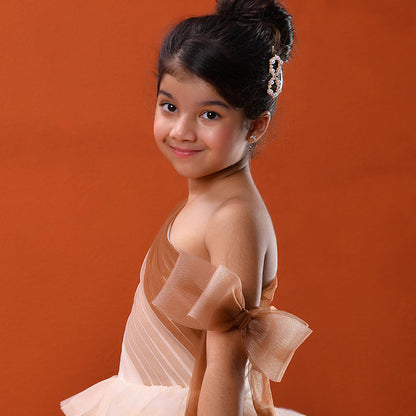 Young girl in a beige dress with a large bow on an orange background