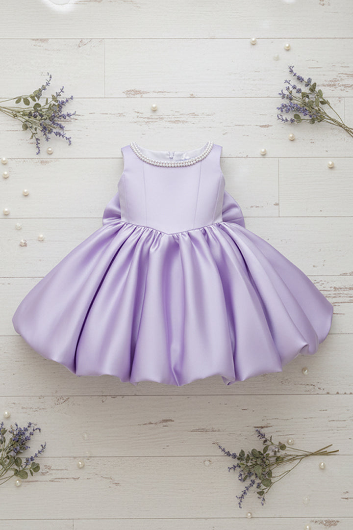 Lavender dress on a white wooden surface with small flowers around
