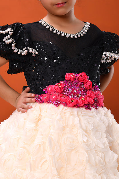 Child wearing a black sequined top with a pink floral and bead embellished waistband against an orange background.