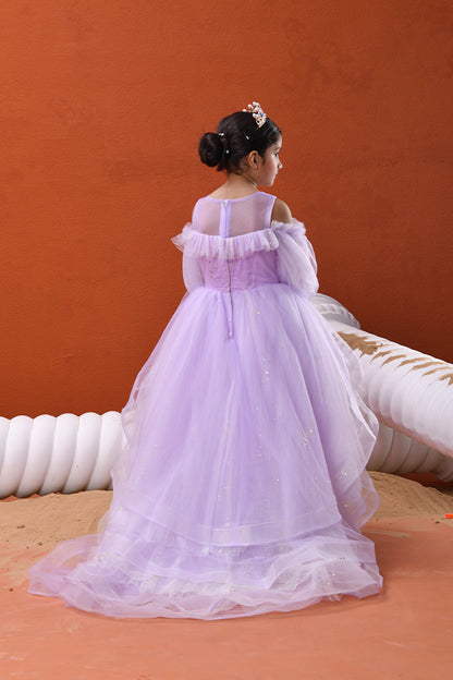 Young girl in a purple dress standing against an orange wall.