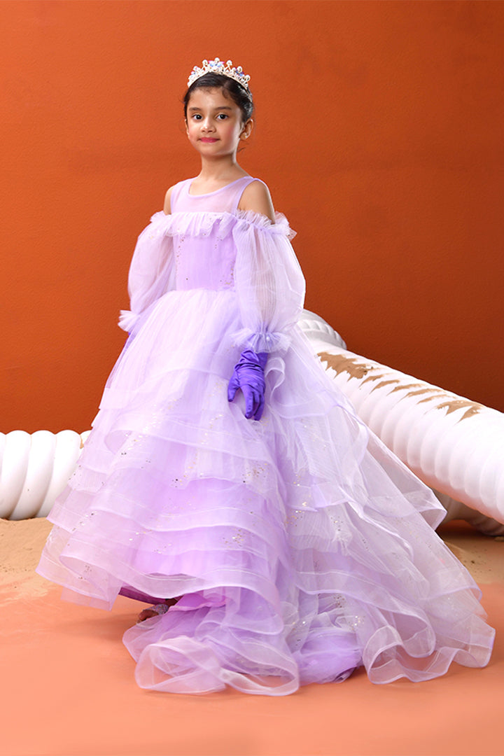 Young girl in a purple and white dress with a tiara against an orange background