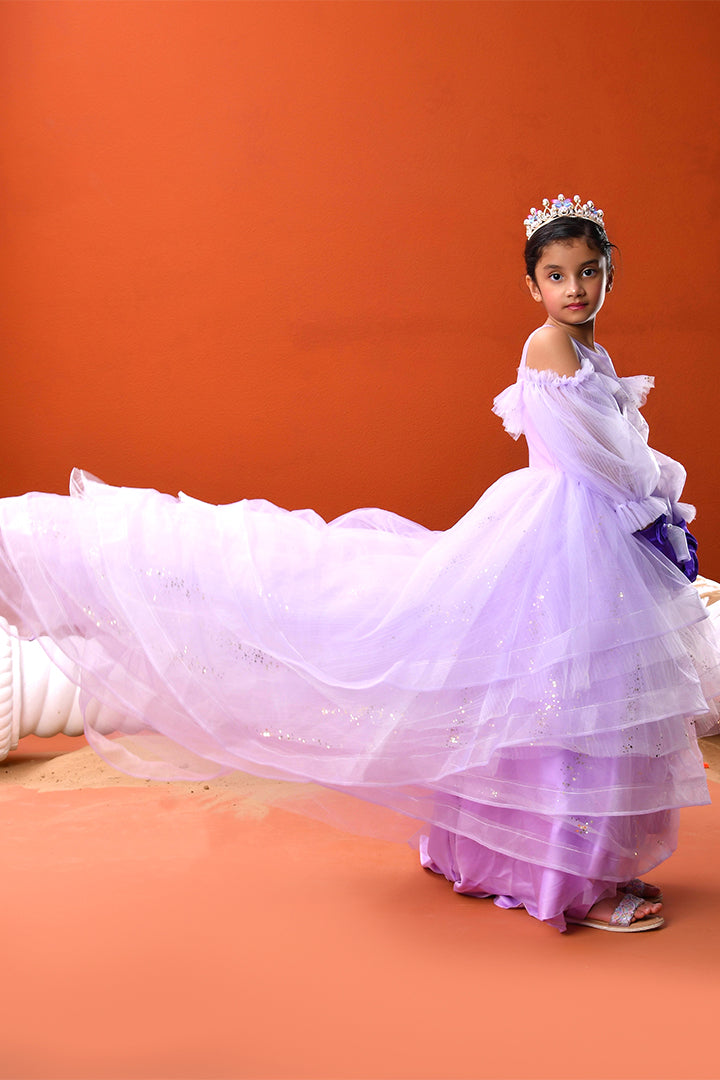 Young girl in a purple dress with a tiara against an orange background