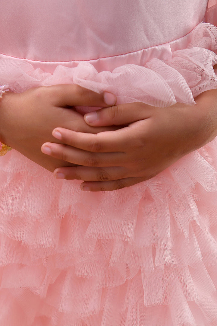 Close-up of a person wearing a pink dress with ruffled layers.
