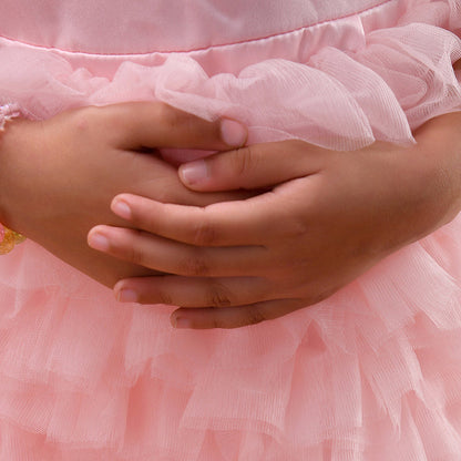 Close-up of a person wearing a pink dress with ruffled layers.