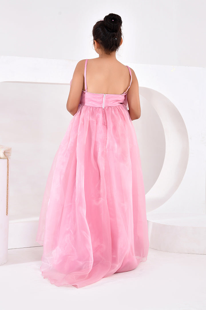 Woman wearing a pink dress sitting on a white chair against a white background