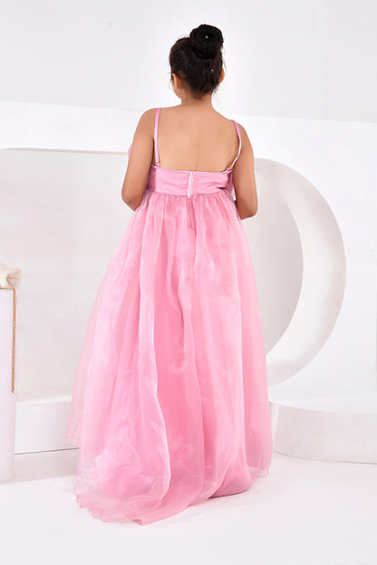 Woman wearing a pink dress sitting on a white chair against a white background