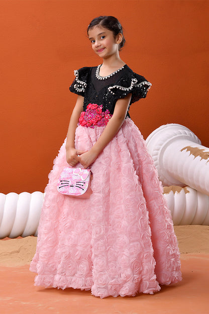 Young girl in a black and pink dress with floral details against an orange background
