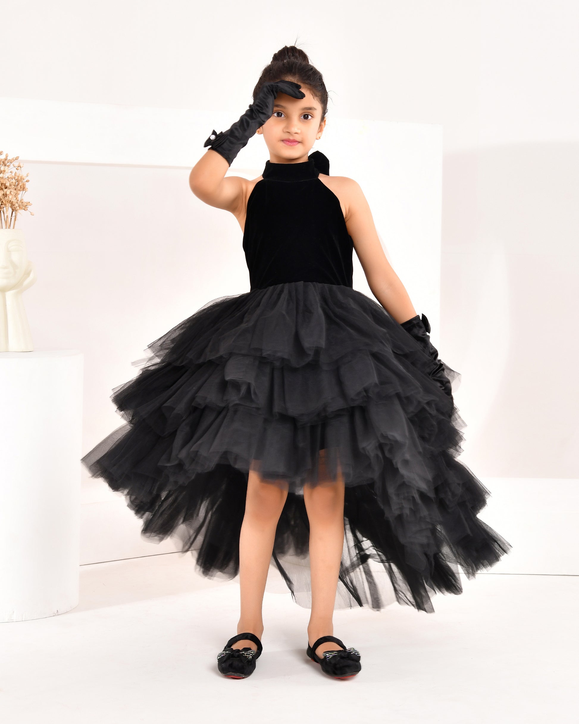 a young girl wearing black high low dress from nibblekins with white background 
