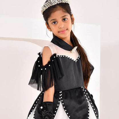 Young girl in a black and white gown with a tiara on a plain background