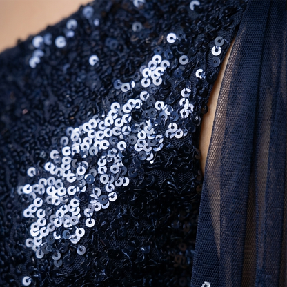 Close-up of a dark navy sequined garment with a sheer navy tulle panel, showing the texture of the sequins and fabric.