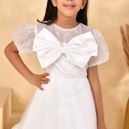 Young girl wearing a white dress with a large bow on a beige background