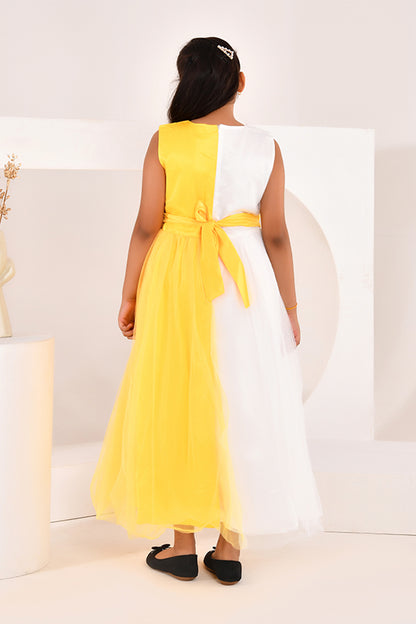 Woman wearing a yellow and white dress sitting on a white couch.